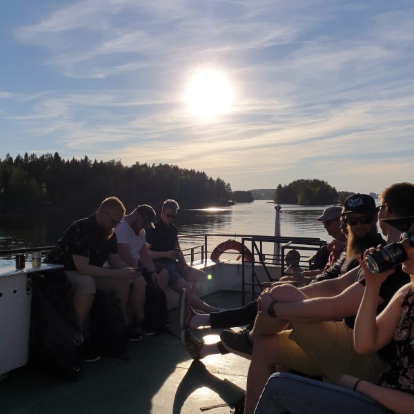 Hurja Solutions kesäpäivä työntekijät laivan kannella auringonlaskussa.